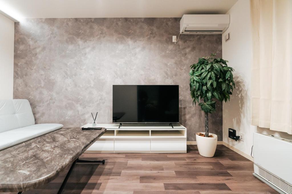 a living room with a flat screen tv on a wall at T-square旭大前I in Asahikawa