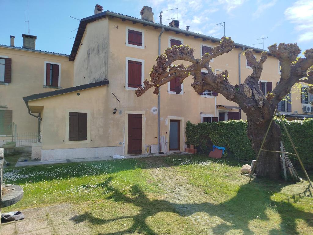 a large house with a tree in front of it at B&Bee alla corte in Dossobuono