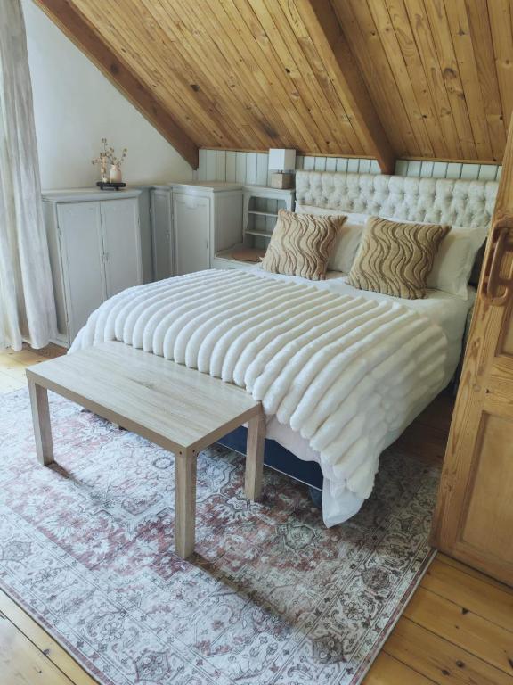 a large white bed with a bench in a room at Mienru House Self Catering Cottage in Riviersonderend