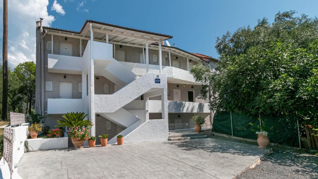 a white building with a staircase in front of it at Alexandros Apartments in Ipsos