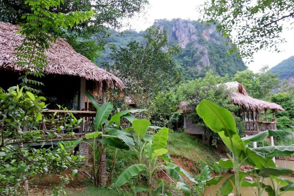 a group of huts with mountains in the background at Thái Tâm homestay in Mai Châu