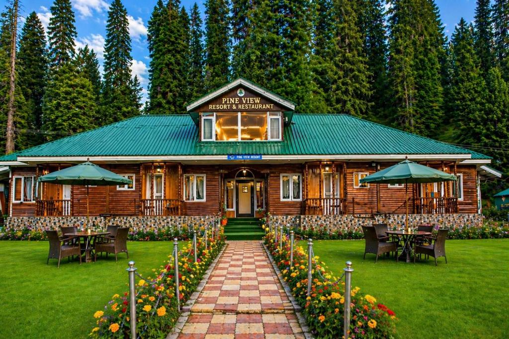 a log cabin with tables and umbrellas in front of it at Pine View Resort in Gulmarg