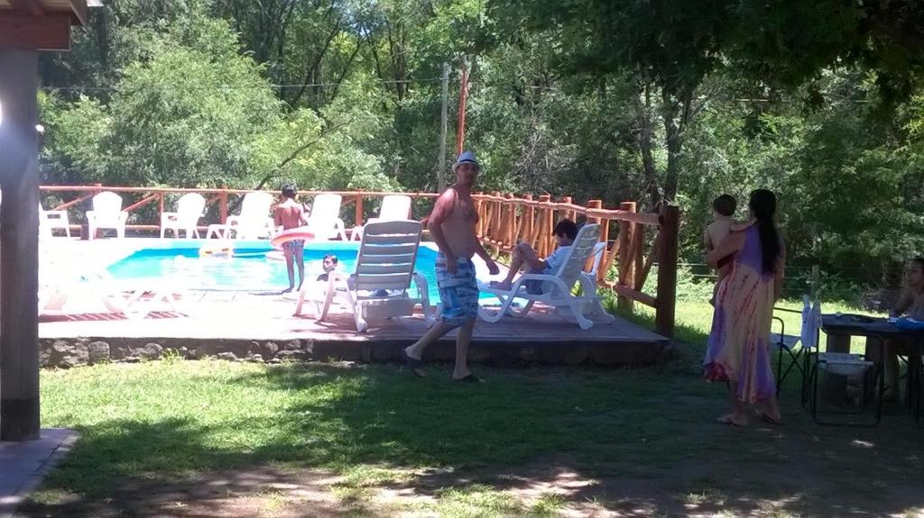 a group of people standing around a swimming pool at Cabañas Buen Dia in Villa Serranita