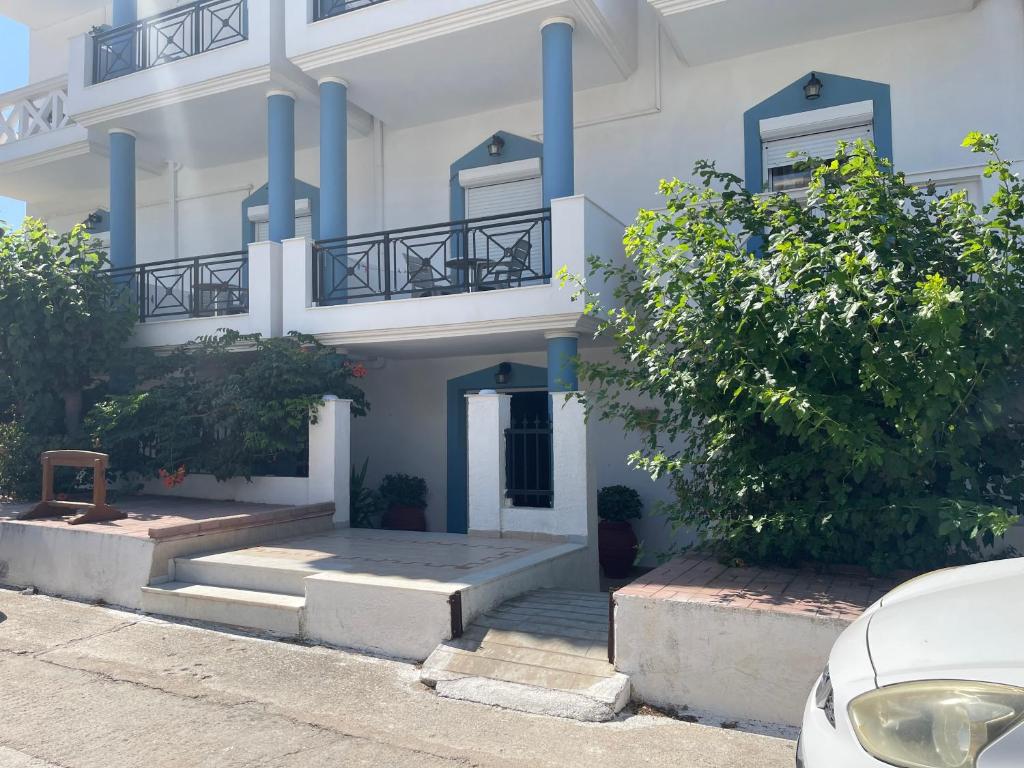 a white building with blue columns and stairs in front at Plaka Apartments in Fournoi