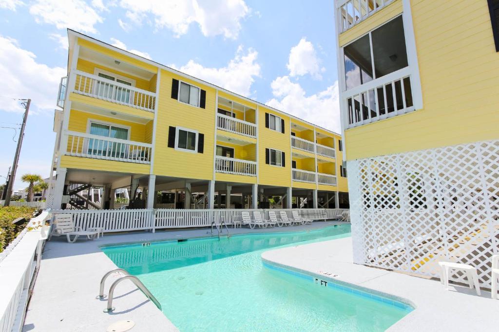 ein großes gelbes Gebäude mit einem Pool neben einem Gebäude in der Unterkunft Sandy Shores III by Capital Vacations in Myrtle Beach