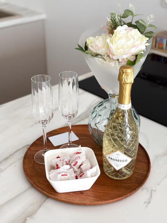 a wooden tray with a bottle of wine and glasses at Omega Lake Apartament Olsztyn in Olsztyn