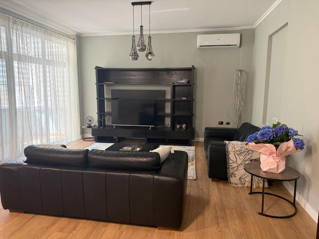 a living room with a black leather couch and a television at Maya's home Tirana in Tirana