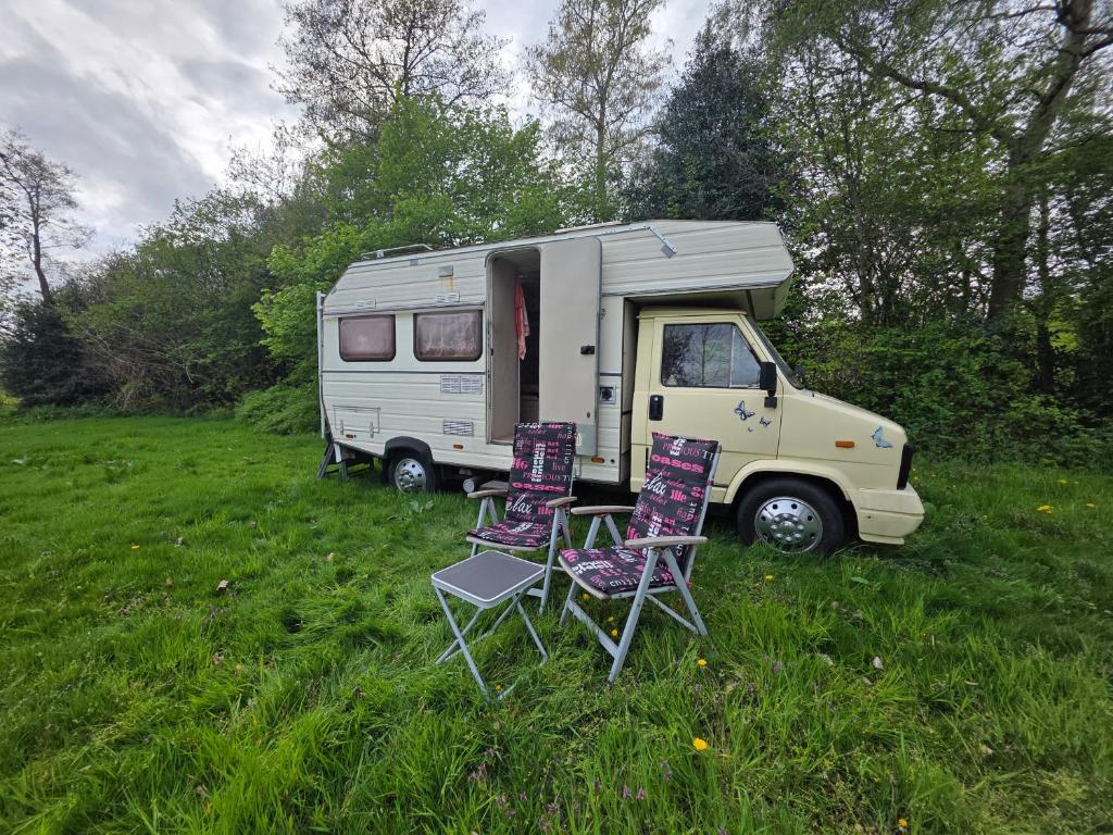 two chairs and an rv parked in a field at Bed and Breakfast Reestdal in Meppel