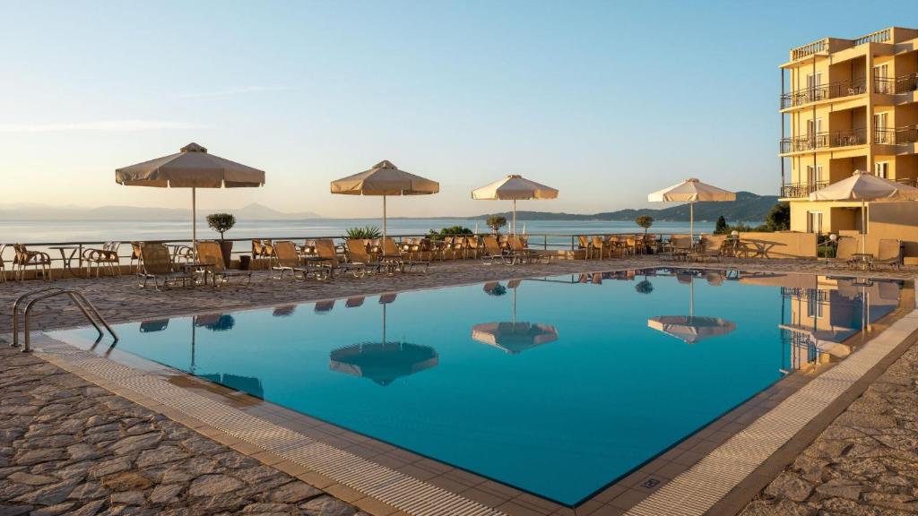 a large swimming pool with tables and umbrellas at Canvas by Mitsis Belvedere in Benitses