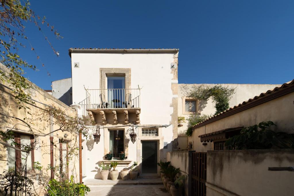 a white building with a balcony on a street at Casa Philomena - Fascino storico in centro in Noto