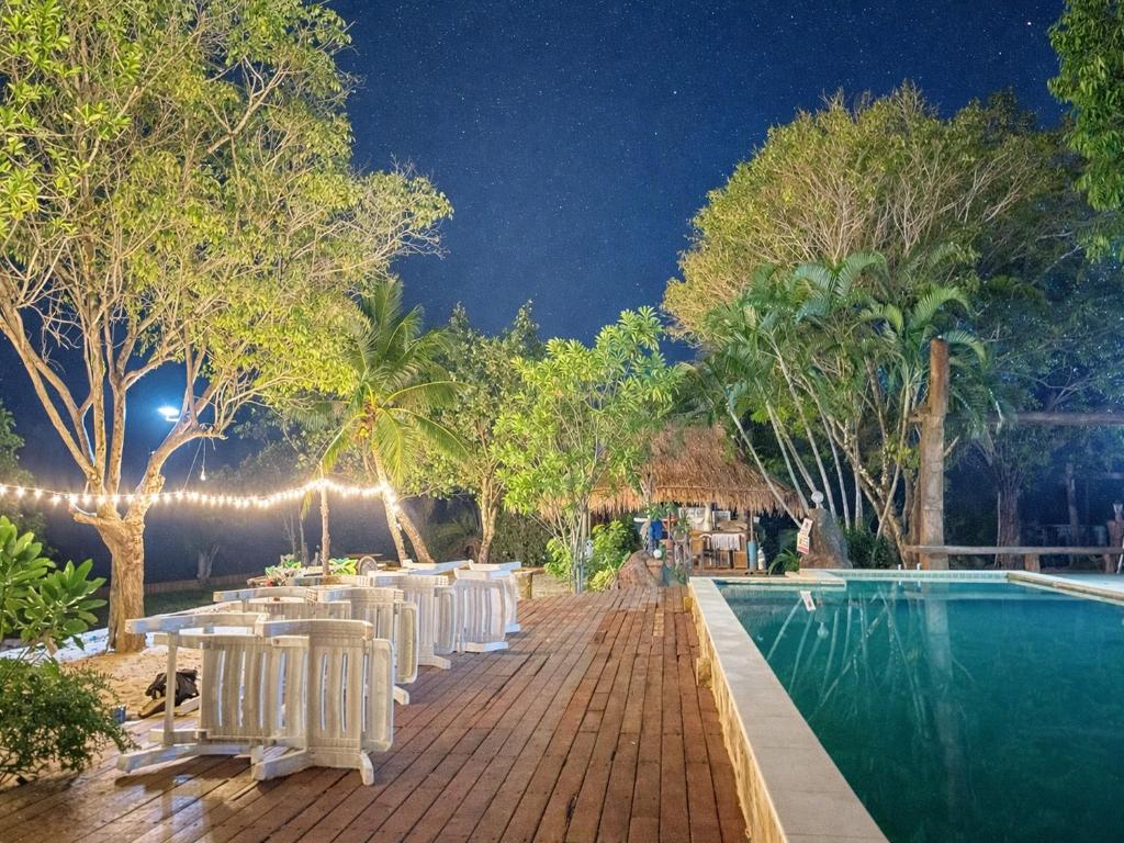 a row of white chairs next to a pool at night at Moonlit Garden Koh Chang in Ban Dan Kao