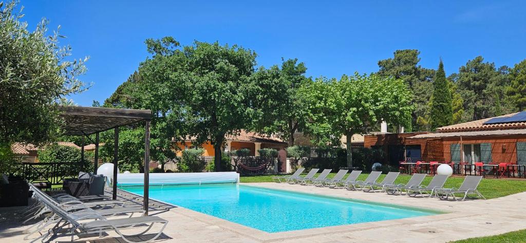 a swimming pool with lounge chairs next to a house at Les Sables d'Ocre & SPA in Roussillon