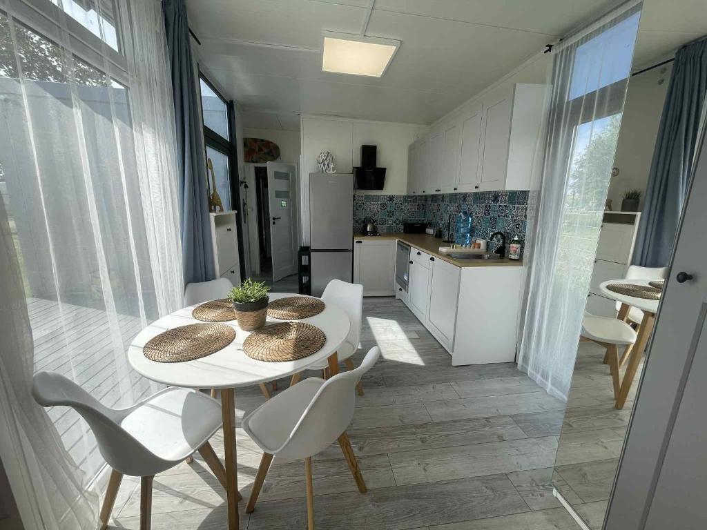 a kitchen and dining room with a table and chairs at Surf Osada, komfortowe domki w kameralnej okolicy nad samym brzegiem Zatoki Puckiej in Swarzewo