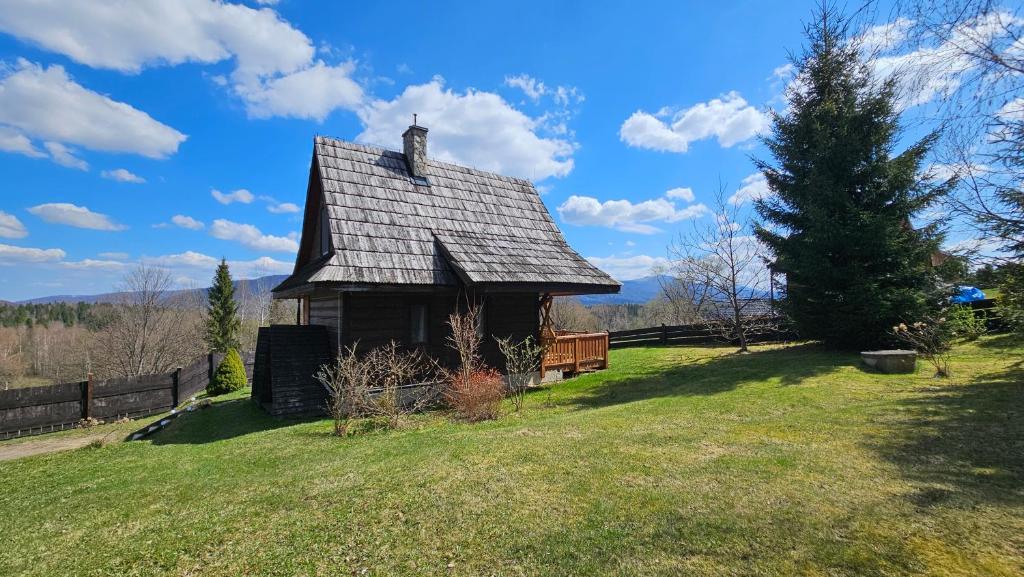 an old house in a field with a tree at Chatka Kudłatka in Wetlina