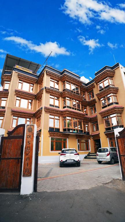 a building with two cars parked in a parking lot at Hotel DE Suzain-Leh in Leh