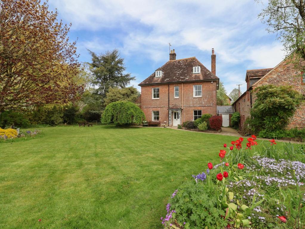 an old brick house with a yard with flowers at Gould's Farmhouse in Blandford Forum