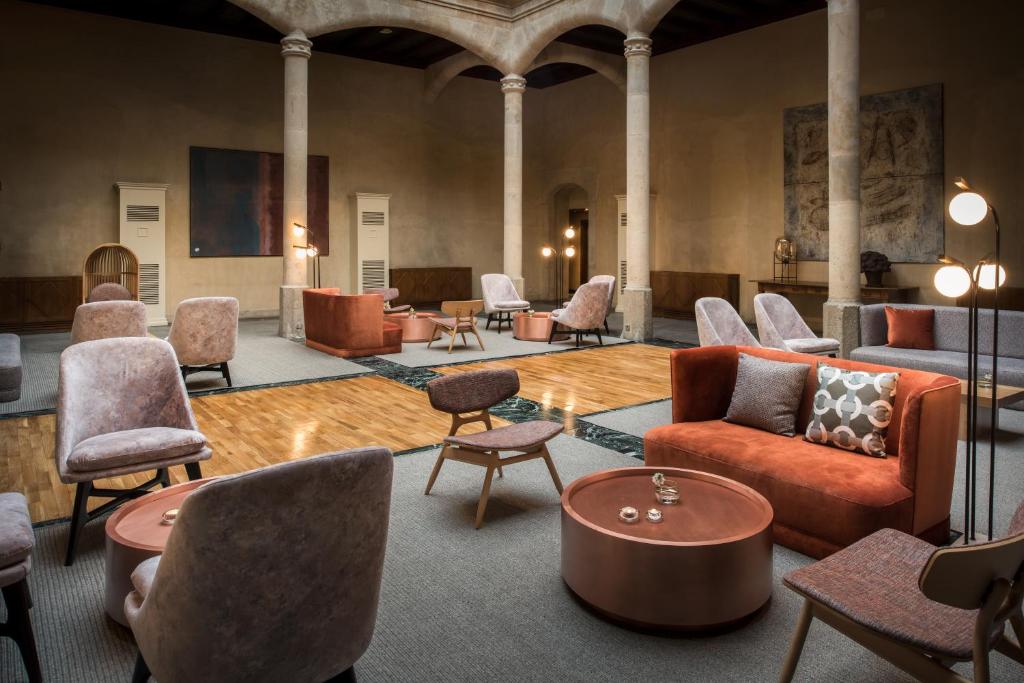 a lobby with chairs and couches and tables at NH Collection Salamanca Palacio de Castellanos in Salamanca