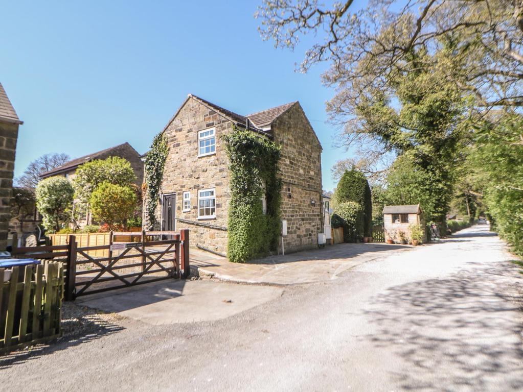 a large brick house with a gate and a driveway at Pine Cottage in Hathersage
