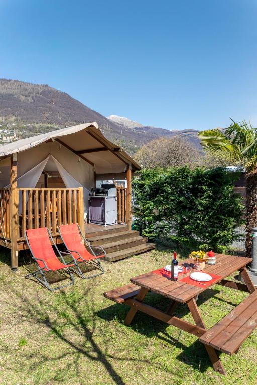 a picnic table and chairs in front of a house at Glamping Italia 90 Mini Lodges in Domaso