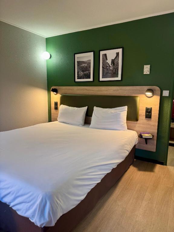 a bedroom with a large bed with a green wall at Campanile NATURE -Haguenau in Haguenau