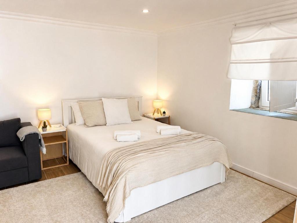 a bedroom with a bed and a chair and a window at Modern Studio with Private Patio near Cascais & Sintra in Alcabideche
