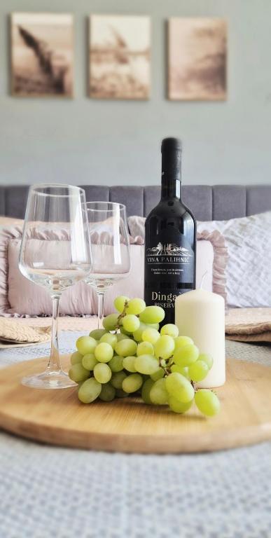 a bunch of green grapes on a table with wine glasses at Apartman Ivano in Vukovar