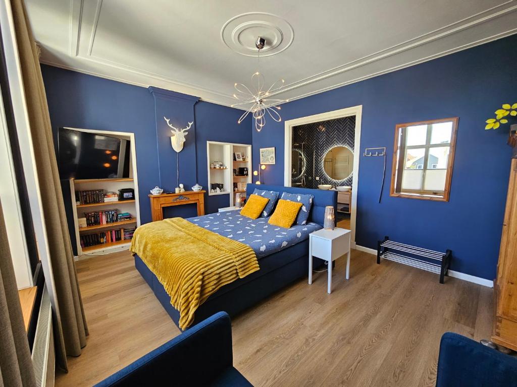 a bedroom with blue walls and a bed with yellow pillows at B&B van Zon aan Zee in Vlissingen