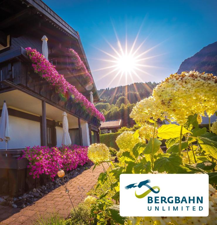a building with flowers and the sun in the background at Hotel Liberia in Oberstdorf