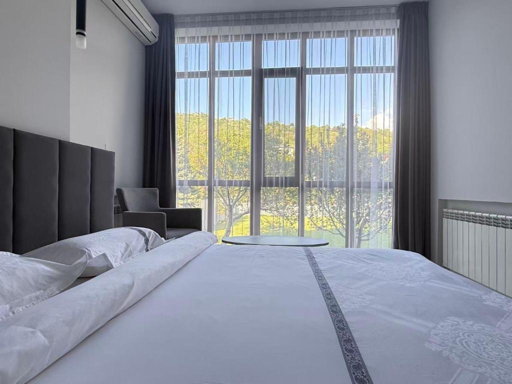a bedroom with a large bed with a large window at Green Hill Hotel in Almaty