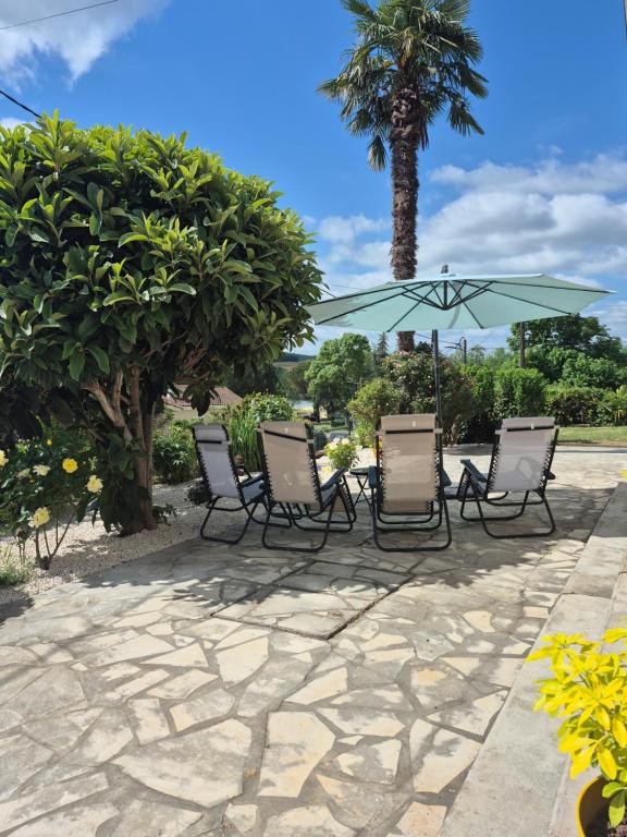 a group of chairs and an umbrella on a patio at Lake Villa Castéra-Verduzan in Castéra-Verduzan