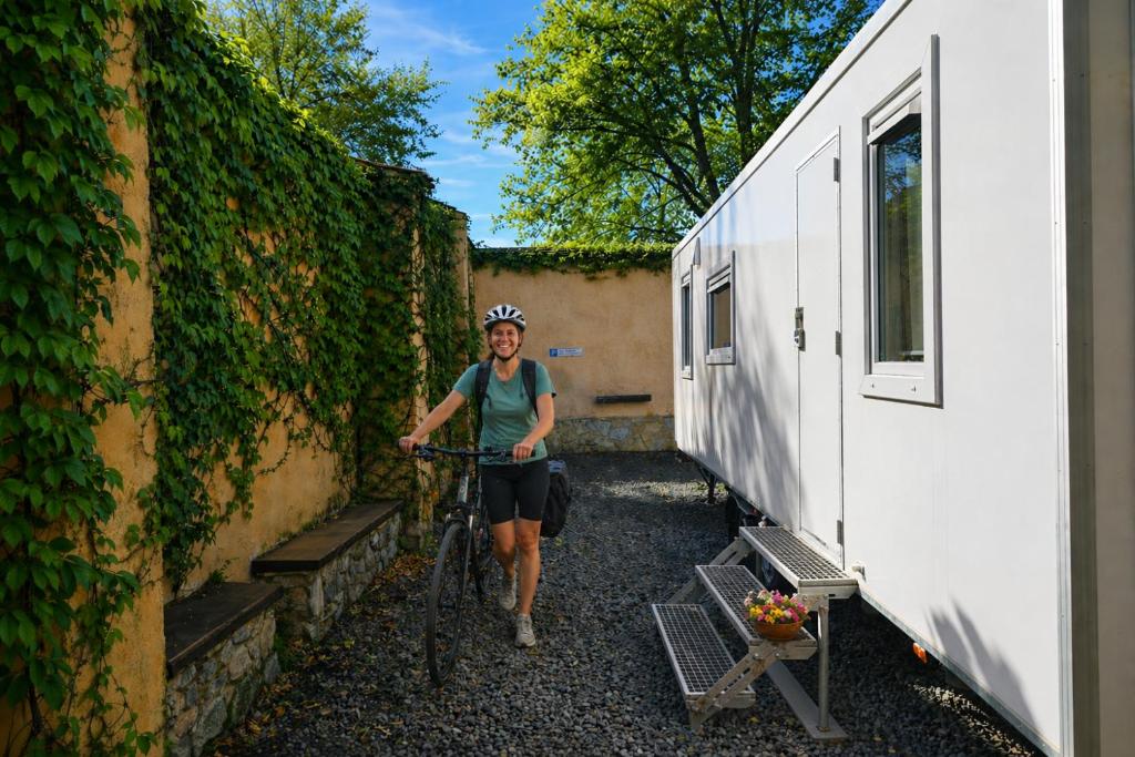a woman walking her bike next to a building at Weinschlafwagen Bautzen in Bautzen