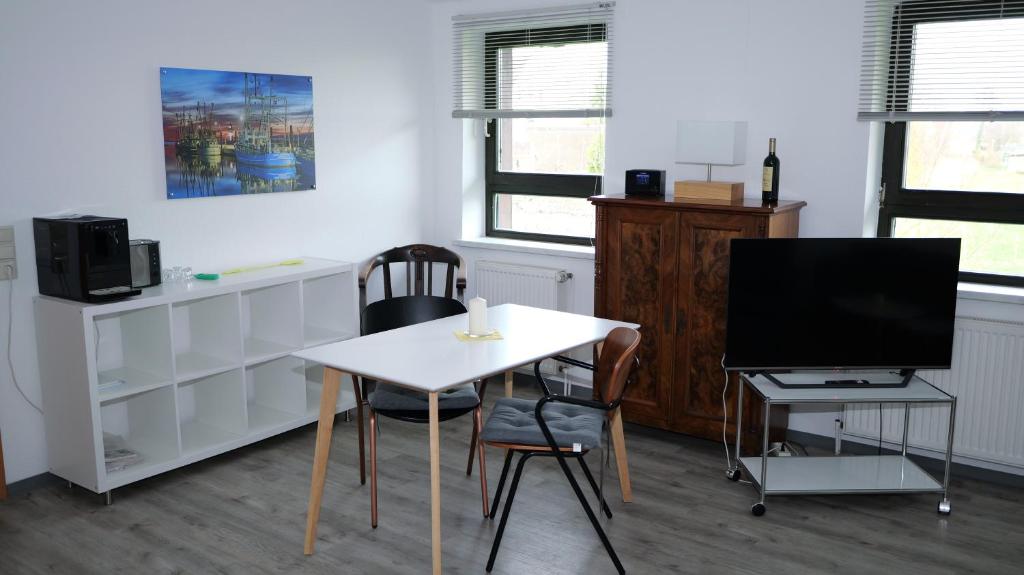 a living room with a white table and a television at Appelholt in Wremen