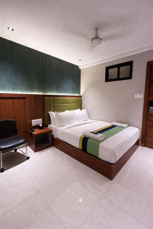 a bedroom with a large bed and a chair at Ruby Hotel in Mumbai