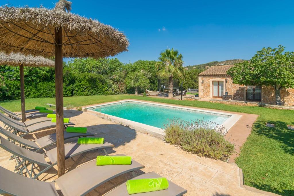 a pool with chairs and an umbrella and a swimming pool at Sa Punta in Son Carrió