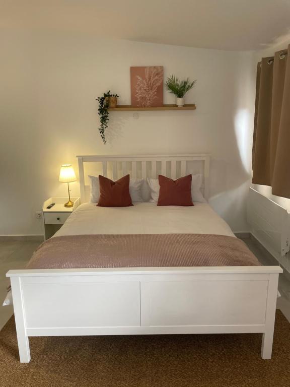 a white bed with red pillows in a bedroom at Chene Résidence Viry chatillon in Viry-Châtillon