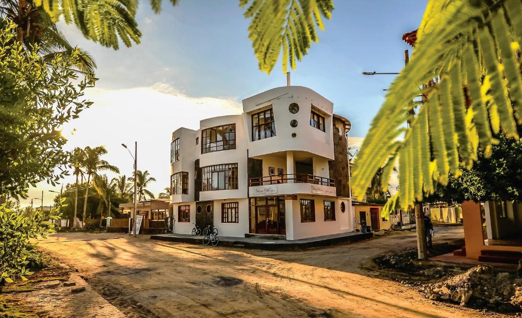 a large white building on a dirt road at Hotel Volcano in Puerto Villamil