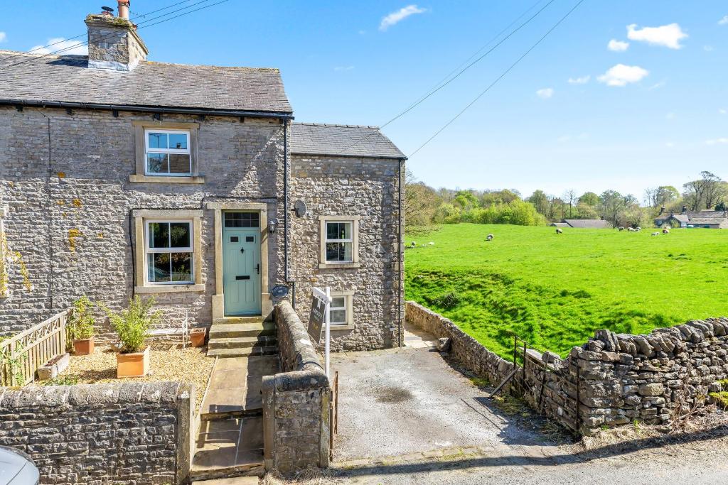 a stone house with a blue door and a field at John Brown Cottage in Skipton