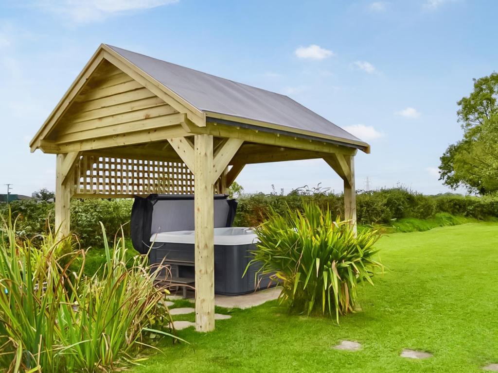 a wooden gazebo with a tv in the grass at Angerton Cottage in Carlisle