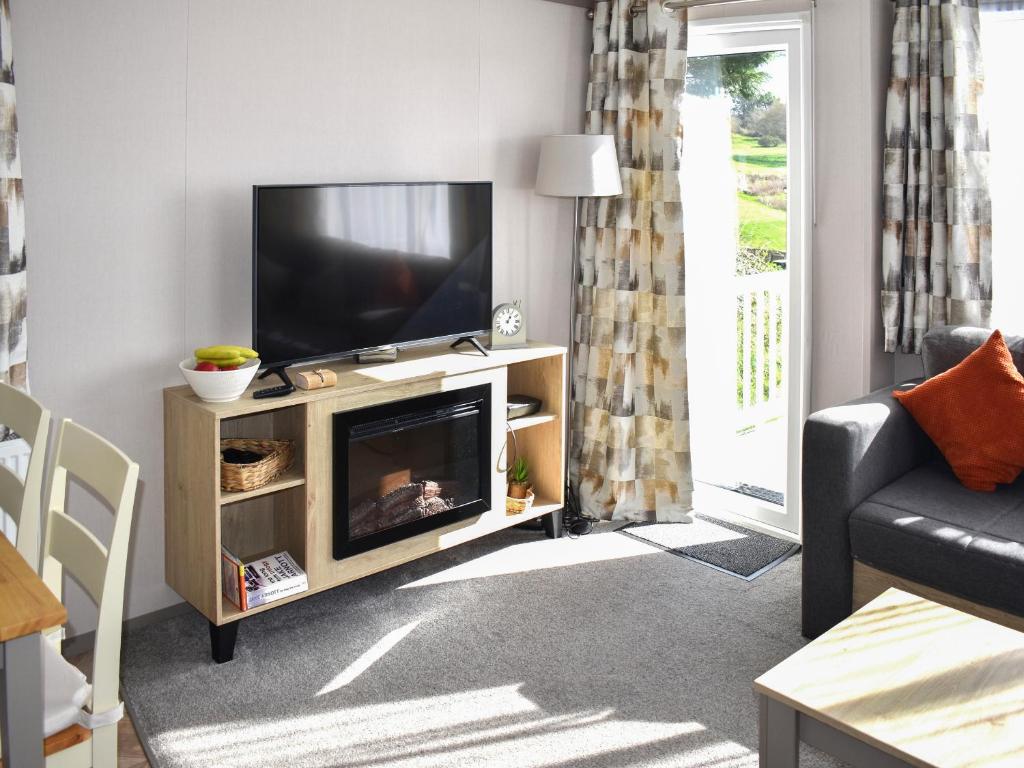 a living room with a flat screen tv on a entertainment center at Lodge 33 in Woolacombe