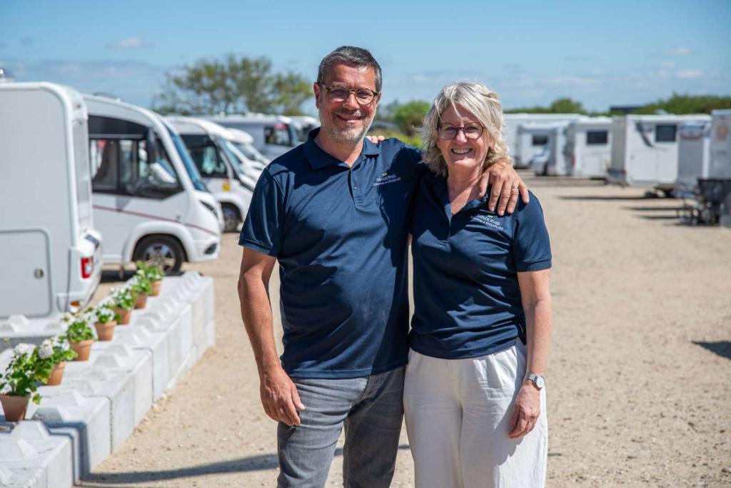a man and a woman standing in front of a parking lot at Søndervig Camping & Cottages in Søndervig