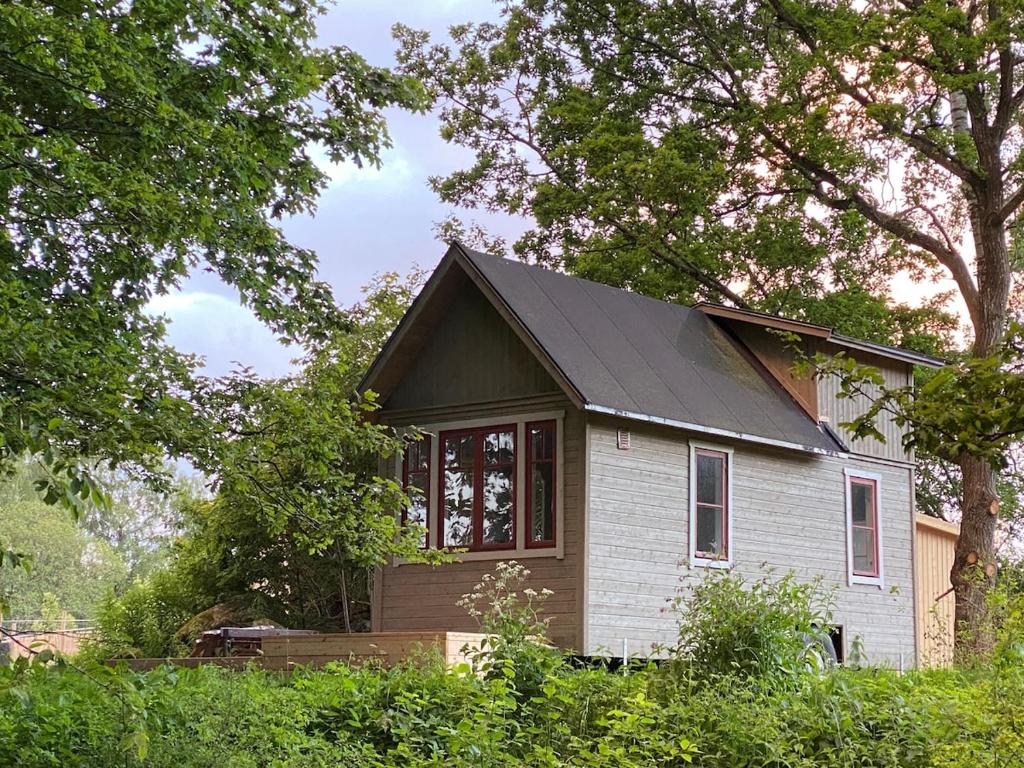 a small white house with a black roof at Fint Tiny house på Österlen in Sankt Olof