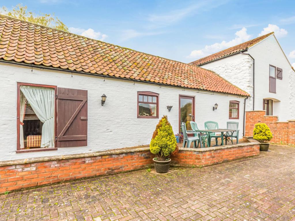 a white house with a patio and a table and chairs at Anvil Cottage in Louth