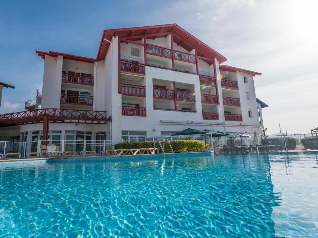 a hotel with a swimming pool in front of a building at Résidence Mer & Golf Sokoburu in Hendaye