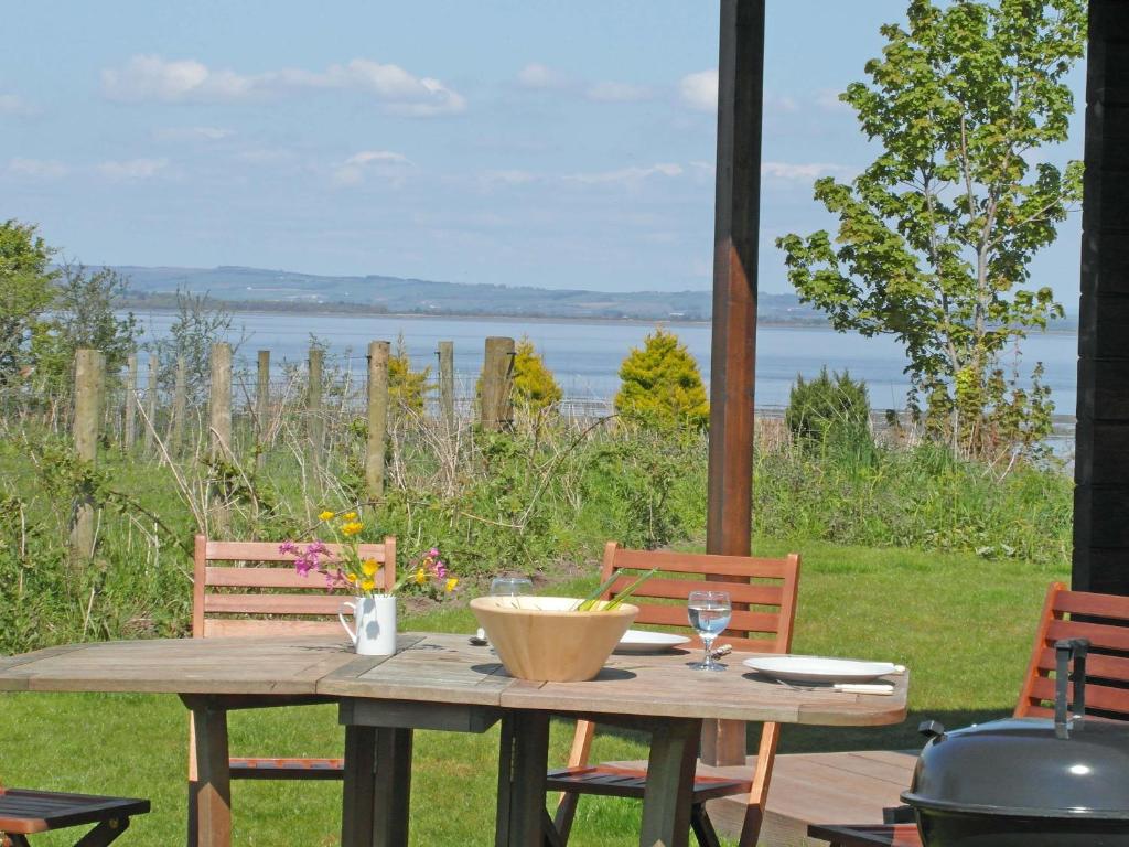 a wooden table with two chairs and a view of the water at Lapwing Lodge - Uk51640 in Carsethorn