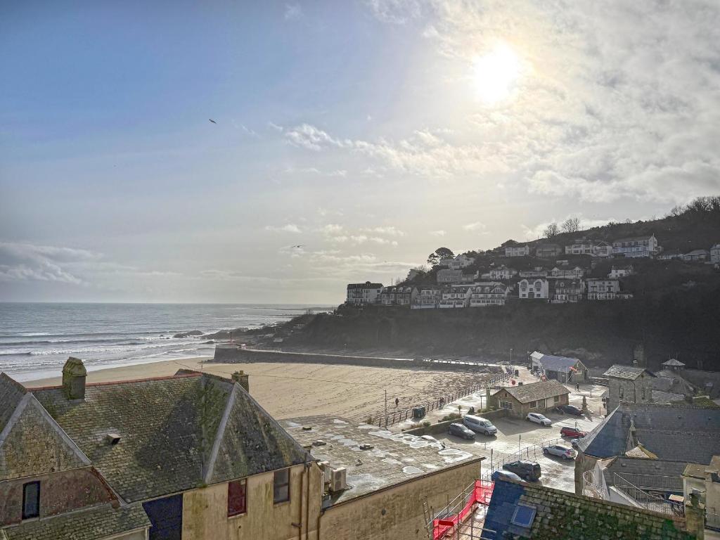 a view of a beach with buildings and the ocean at Gwendrock Diw in Looe