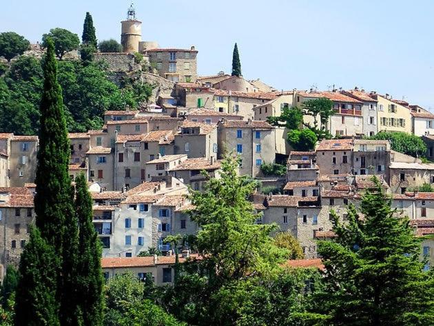 a group of buildings on a hill with trees at Studio in Fayence