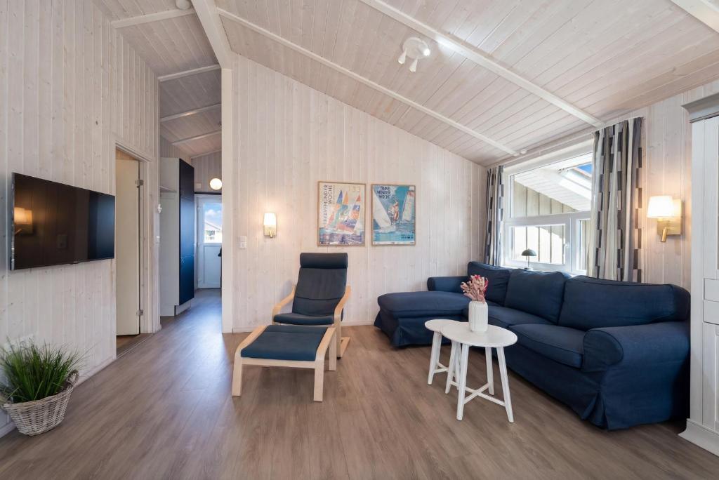 a living room with a blue couch and a table at Schmugglerstieg - Dorf Ferienhaus 03 in Priwall