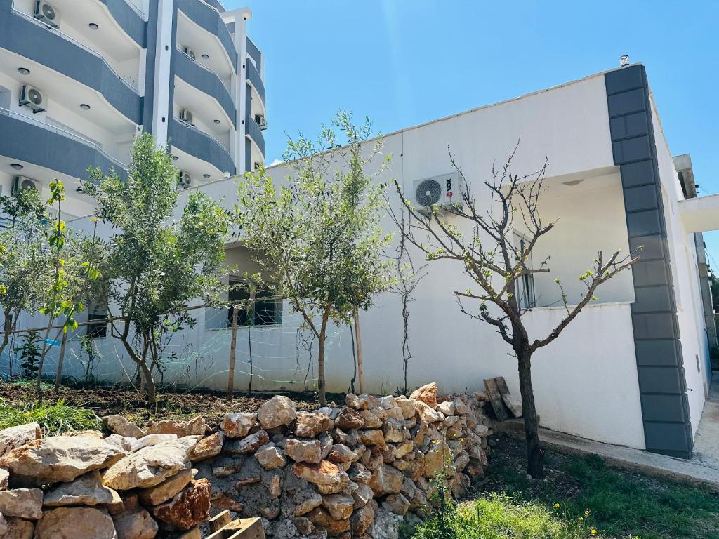a building with trees next to a pile of rocks at Garden studio apartmans in Dobra Voda