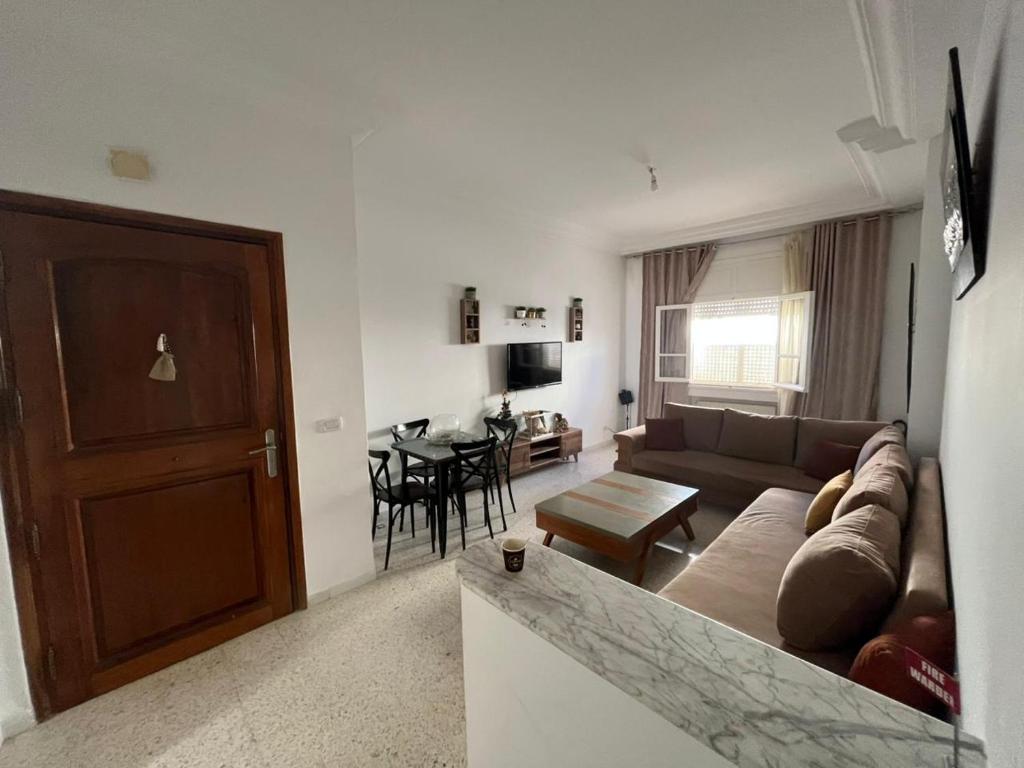 a living room with a couch and a table at Cozy house in El Aouina Station