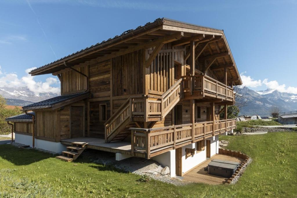a large wooden house with a large deck at Chalet Suzane - Panorama Mont-Blanc & jacuzzi in Combloux